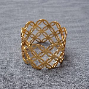 Detail showing hollow flower pattern on a polished gold napkin ring for hotel table decor