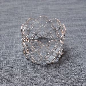 Detail of silver hollow geometric napkin ring with overlapping circular metal pattern