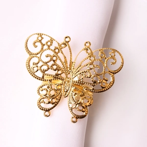 Elegant gold butterfly napkin ring with hollow floral patterns on white fabric napkin