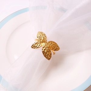 Gros plan d'un rond de serviette papillon doré avec texture de feuille sur assiette