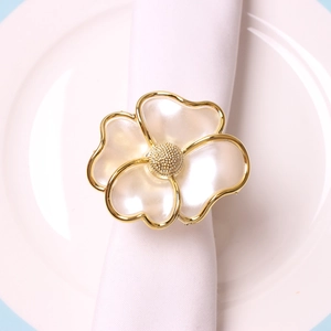 Elegant gold-plated flower napkin ring with pearl petals on white linen napkin