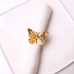 Detail of a gold butterfly napkin ring featuring polished metal texture and wings