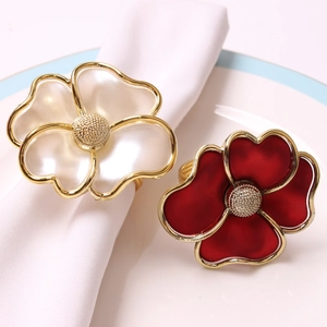 Elegant floral pearl napkin rings in red and white colors on a white ceramic dinner plate