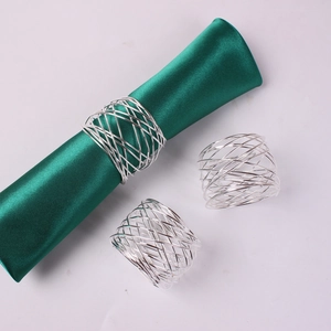 Close-up of silver mesh wire napkin rings styled with green satin fabric on a grey background
