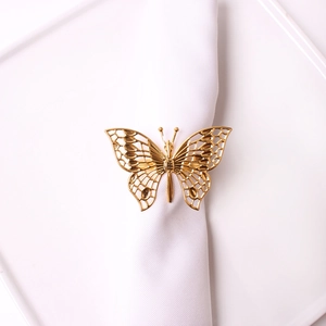 Detailed view of hollow gold butterfly napkin ring on white dinnerware for elegant banquet