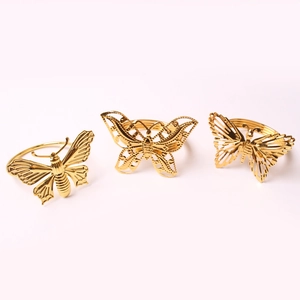 Detailed view of three hollow butterfly napkin rings in elegant gold plated finish