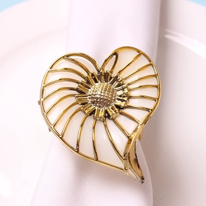 Macro detail of a golden flower napkin ring with white enamel finish on a white fabric