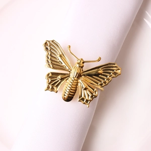 Elegant gold butterfly napkin ring with detailed wings on a white linen napkin and plate