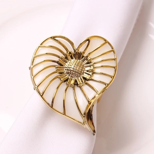Detail of flower napkin ring with gold heart frame and white enamel inlay on linen