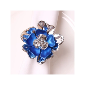 Rond de serviette fleur bleu et doré élégant posé sur une serviette en tissu blanc