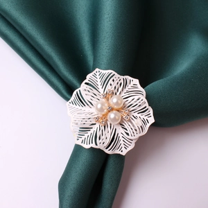 Macro view of white floral napkin ring with pearls and rhinestones on green silk