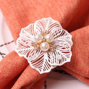 Elegant white hollow flower napkin ring with pearls and rhinestones on a table