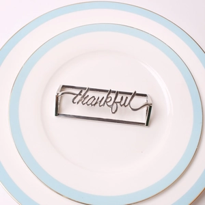 Close-up of silver metal thankful napkin ring on white ceramic plate for table setting