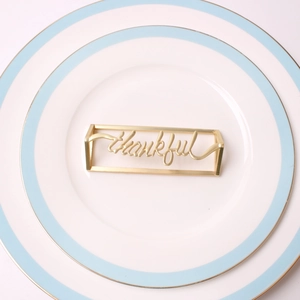 Macro shot of golden metal thankful napkin ring on white plate for table setting