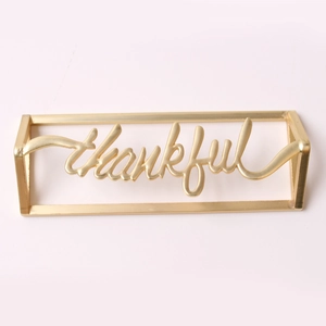 Detailed view of a golden thankful napkin ring with elegant cursive metal lettering