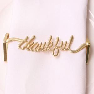 Macro shot of gold 'thankful' napkin ring on white linen napkin for table setting