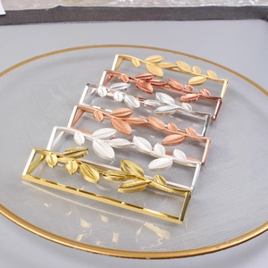 Detail of metal leaf napkin rings in gold, silver and rose gold finish on a tray