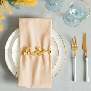 Golden ginkgo leaf napkin ring on marble plate with elegant gold cutlery setting