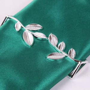 Detail of silver leaf napkin ring featuring fine leaf veins on green silk fabric