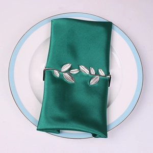 Silver leaf napkin ring on dark green satin napkin over a clean white ceramic plate