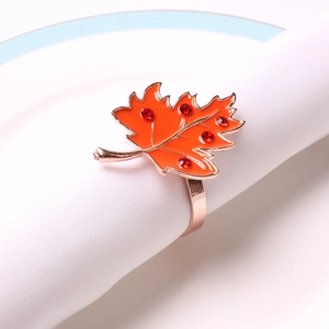 Detail of maple leaf napkin ring with orange enamel and red rhinestones on white cloth