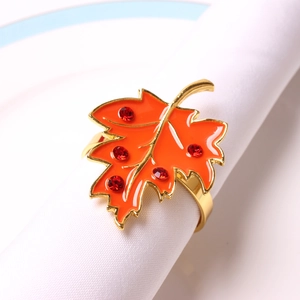 Close-up of orange maple leaf napkin ring with gold metal finish and red crystal accents