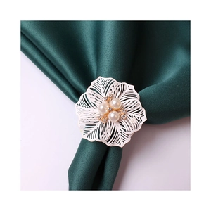 White flower napkin ring with pearls and crystals on green satin fabric background