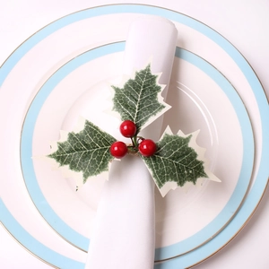 Christmas napkin ring with artificial holly leaves and red berries on a white cloth napkin