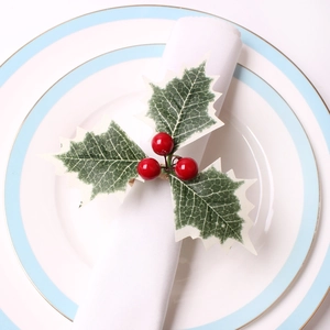 Christmas napkin ring with red berries and frosted green leaves on a white napkin