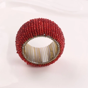 Macro shot of handmade red glass beads woven onto a gold metal napkin ring base