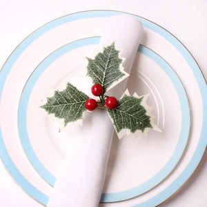Macro detail of Christmas napkin ring with artificial red berries and holly leaves