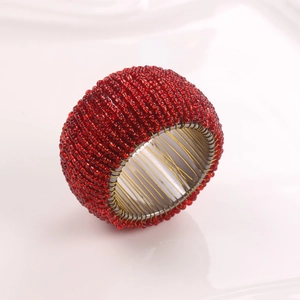 Macro shot of handcrafted red beaded napkin ring showing intricate weave and gold wire