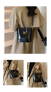 Détail d'un sac seau en cuir noir brillant avec boucle carrée dorée et bandoulière réglable