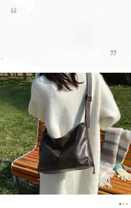 Close-up of the dark brown pleated crossbody bag with adjustable strap in outdoor use