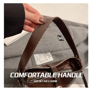 Gros plan du sac seau en cuir marron vintage avec surpiqûres blanches et zip doré brillant