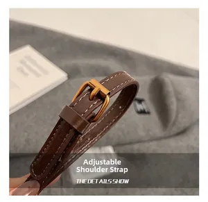 Détail de la bandoulière réglable en cuir marron foncé avec boucle dorée et surpiqûres