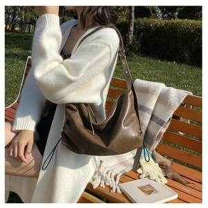 Detailed view of dark brown hobo shoulder bag with vintage pleats and adjustable strap