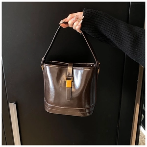 Gros plan d'un sac seau en cuir marron foncé brillant avec boucle dorée vintage