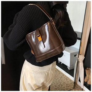 Détail du sac seau en cuir huilé marron foncé avec boucle métallique sur un mannequin