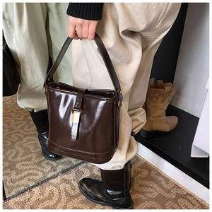 Détail d'un sac seau vintage en cuir marron foncé brillant avec boucles dorées chic