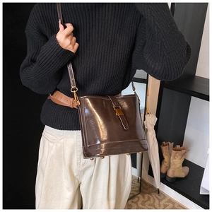 Gros plan du sac seau rétro en cuir marron foncé avec boucles dorées sur modèle