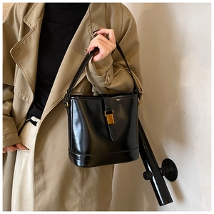 Détail d'un sac seau noir en cuir brillant avec un fermoir en métal doré élégant