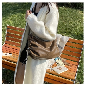 Brown pleated shoulder bag featuring drawstring details and matte leather finish