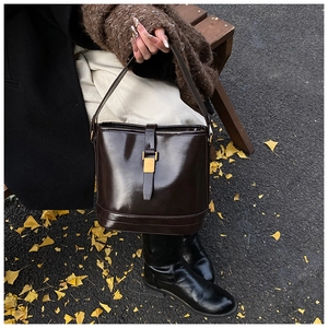 Détail du sac seau marron foncé brillant avec boucles métalliques dorées élégantes