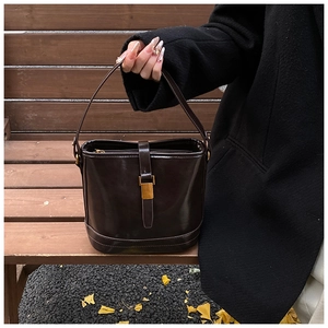 Détail du sac seau vintage marron foncé avec boucle dorée dans un décor d'automne