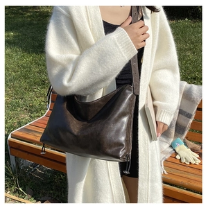 Detail view of large dark brown retro satchel with soft leather texture and metal buckles