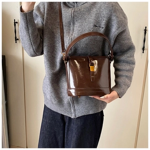 Détail d'un sac seau en cuir marron brillant avec boucle en métal et bandoulière