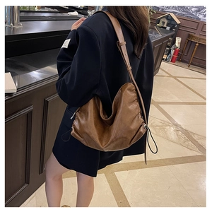 Macro view of retro brown leather shoulder bag with pleated texture and drawstring detail