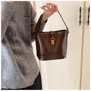 Détail du sac seau en cuir brillant marron foncé avec boucle métallique dorée élégante