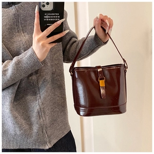 Selfie miroir montrant le sac seau en cuir verni marron foncé brillant à boucle dorée